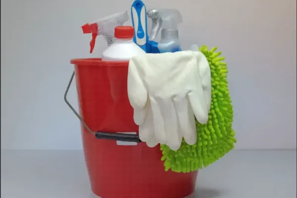 rød rengørings spand med redskaber som spray dåser, hansker og klud